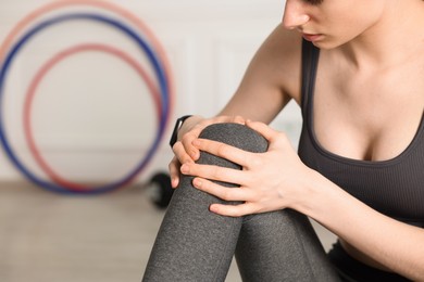 Photo of Sports injury. Young woman suffering from knee pain in fitness studio, closeup. Space for text