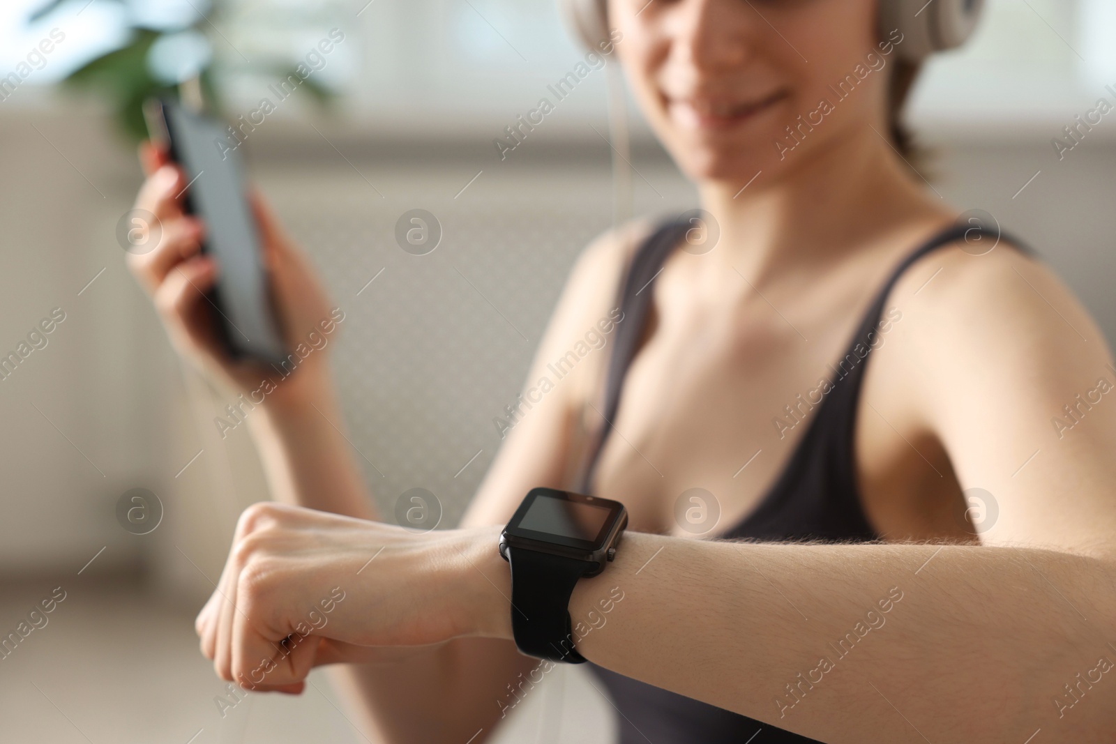 Woman checking fitness tracker during training indoors, closeup Photo of Woman checking fitness tracker during training indoors, closeup