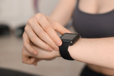 Photo of Woman checking fitness tracker during training indoors, closeup