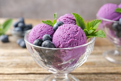Photo of Tasty sorbet with blueberries and mint in dessert bowl on wooden table against grey background, closeup