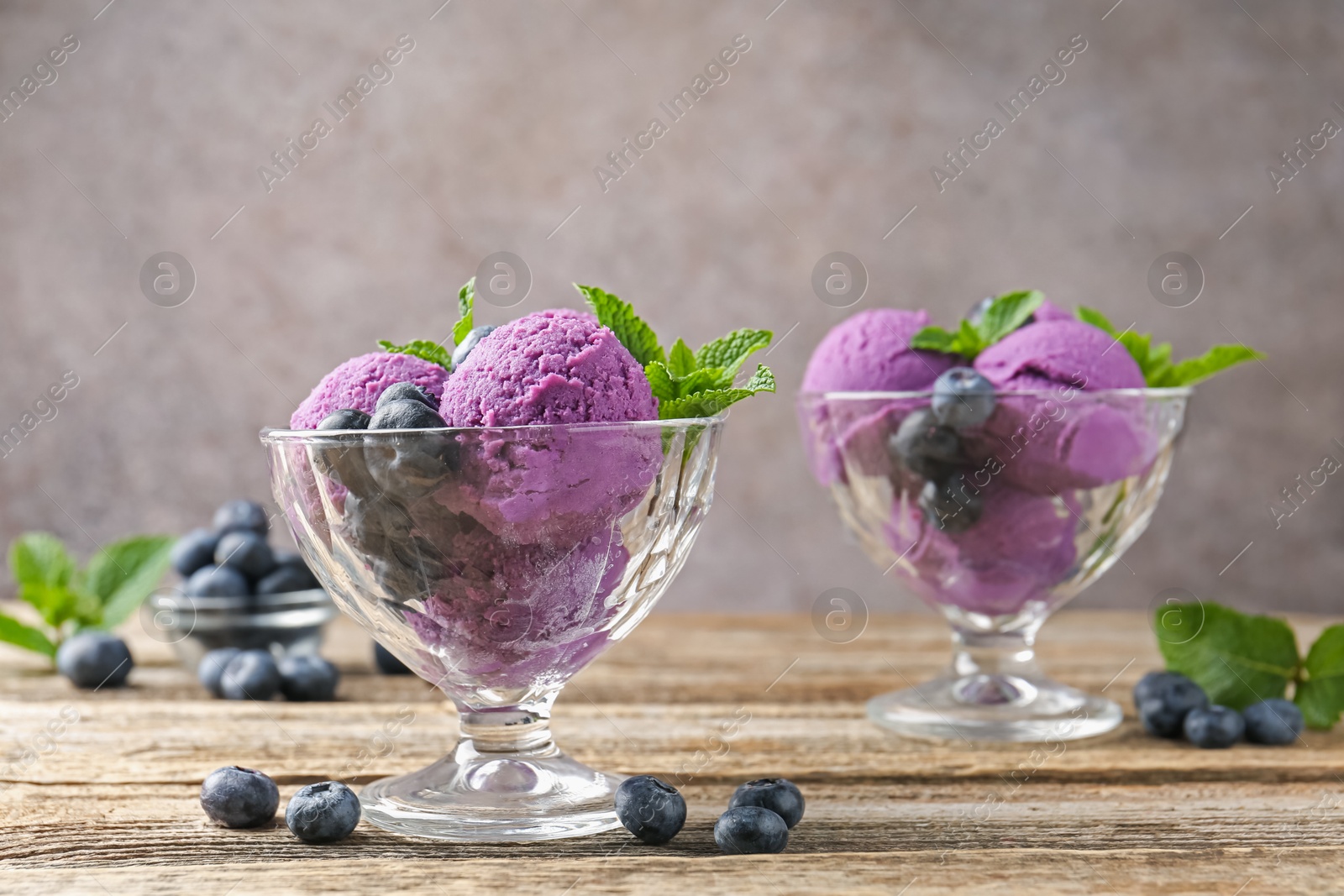 Tasty sorbet with blueberries and mint in dessert bowls on wooden table against grey background, closeup Photo of Tasty sorbet with blueberries and mint in dessert bowls on wooden table against grey background, closeup