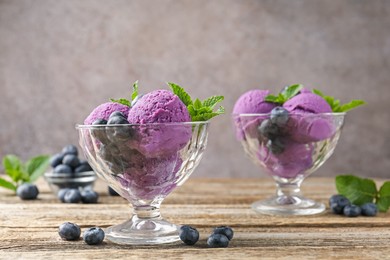 Photo of Tasty sorbet with blueberries and mint in dessert bowls on wooden table against grey background, closeup