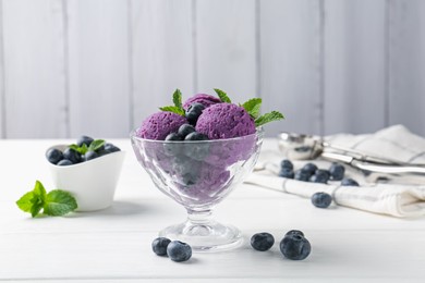 Photo of Tasty sorbet with blueberries and mint in dessert bowl on white wooden table against grey background, closeup