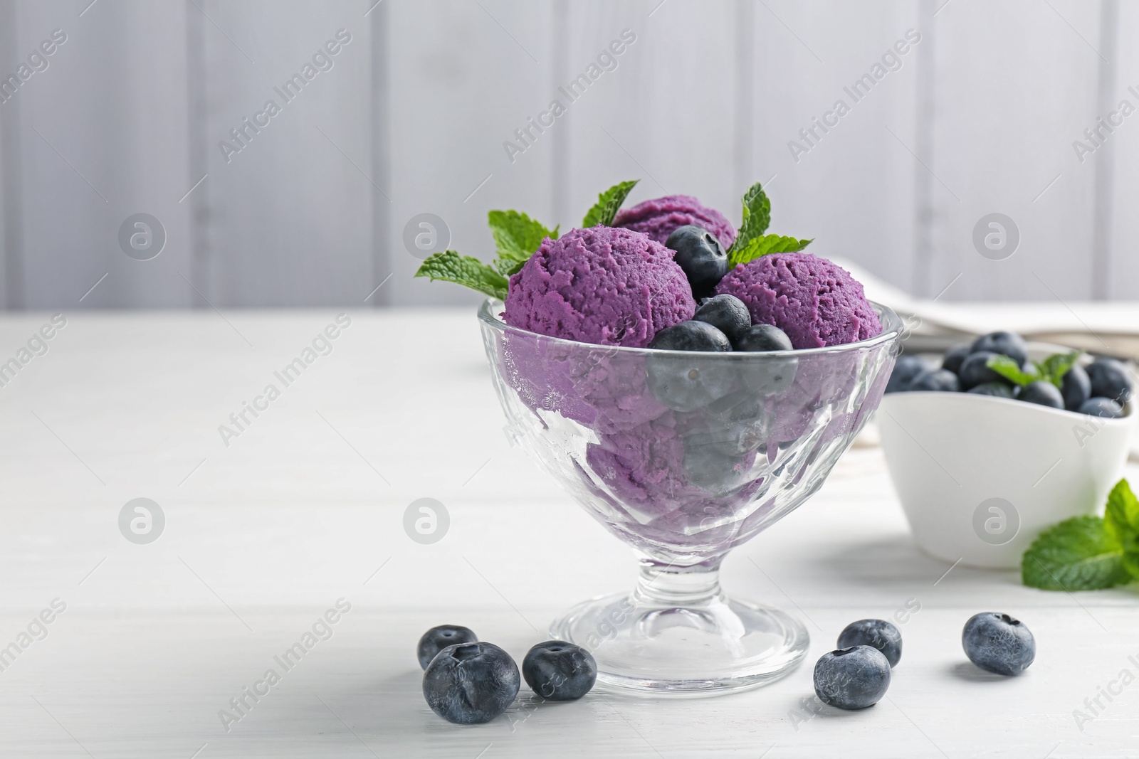 Tasty sorbet with blueberries and mint in dessert bowl on white wooden table against grey background, closeup. Space for text Photo of Tasty sorbet with blueberries and mint in dessert bowl on white wooden table against grey background, closeup. Space for text