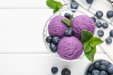 Photo of Tasty sorbet with blueberries and mint in dessert bowl on white wooden table, flat lay. Space for text