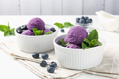 Photo of Tasty sorbet with blueberries and mint in bowls on white table against grey background, closeup