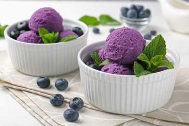 Photo of Tasty sorbet with blueberries and mint in bowls on white table, closeup