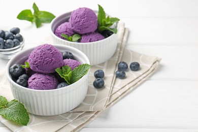 Photo of Tasty sorbet with blueberries and mint in bowls on white wooden table, closeup