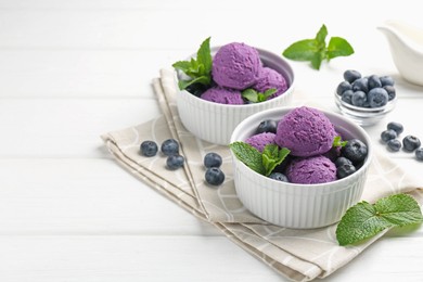 Photo of Tasty sorbet with blueberries and mint in bowls on white wooden table, closeup