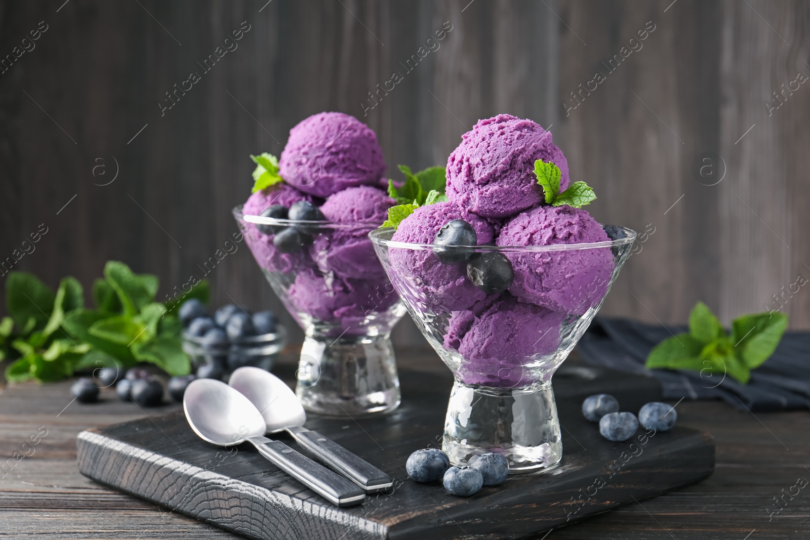 Photo of Tasty sorbet with blueberries and mint in dessert bowls on wooden table, closeup