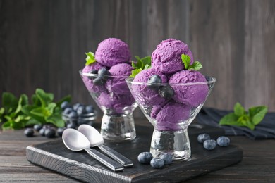 Photo of Tasty sorbet with blueberries and mint in dessert bowls on wooden table, closeup