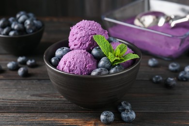 Photo of Tasty sorbet with blueberries and mint in bowl on wooden table, closeup