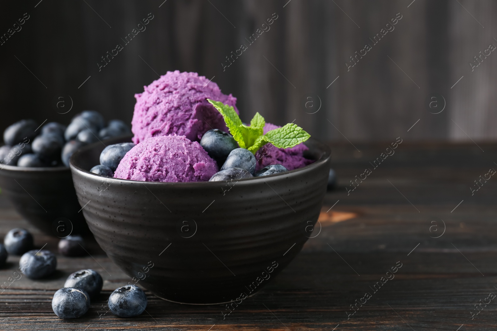 Photo of Tasty sorbet with blueberries and mint in bowl on wooden table, closeup. Space for text