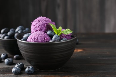 Photo of Tasty sorbet with blueberries and mint in bowl on wooden table, closeup. Space for text