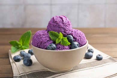 Photo of Tasty sorbet with blueberries and mint in bowl on wooden table, closeup