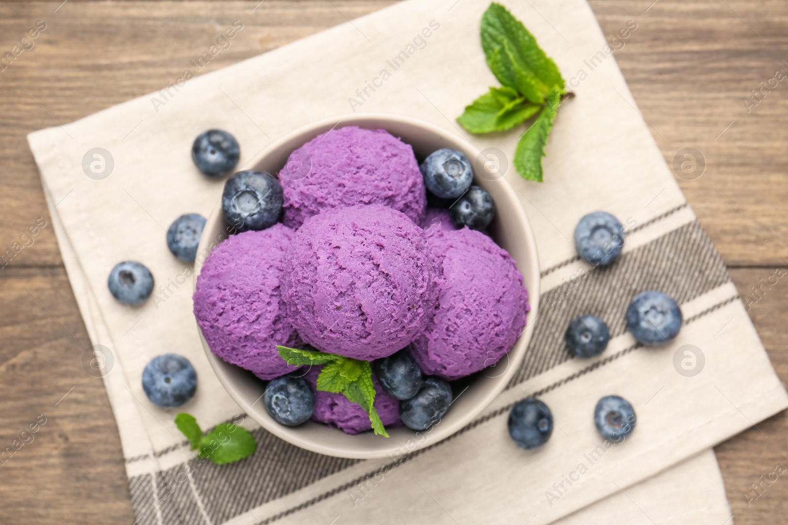 Tasty sorbet with blueberries and mint in bowl on wooden table, top view Photo of Tasty sorbet with blueberries and mint in bowl on wooden table, top view