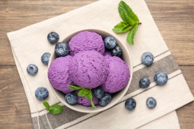 Photo of Tasty sorbet with blueberries and mint in bowl on wooden table, top view