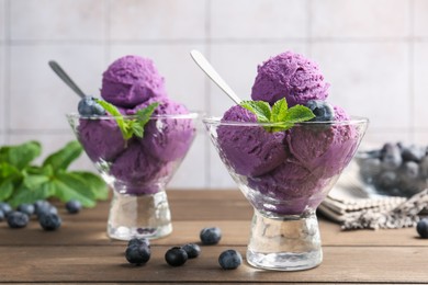 Photo of Tasty sorbet with blueberries and mint in dessert bowls on wooden table, closeup