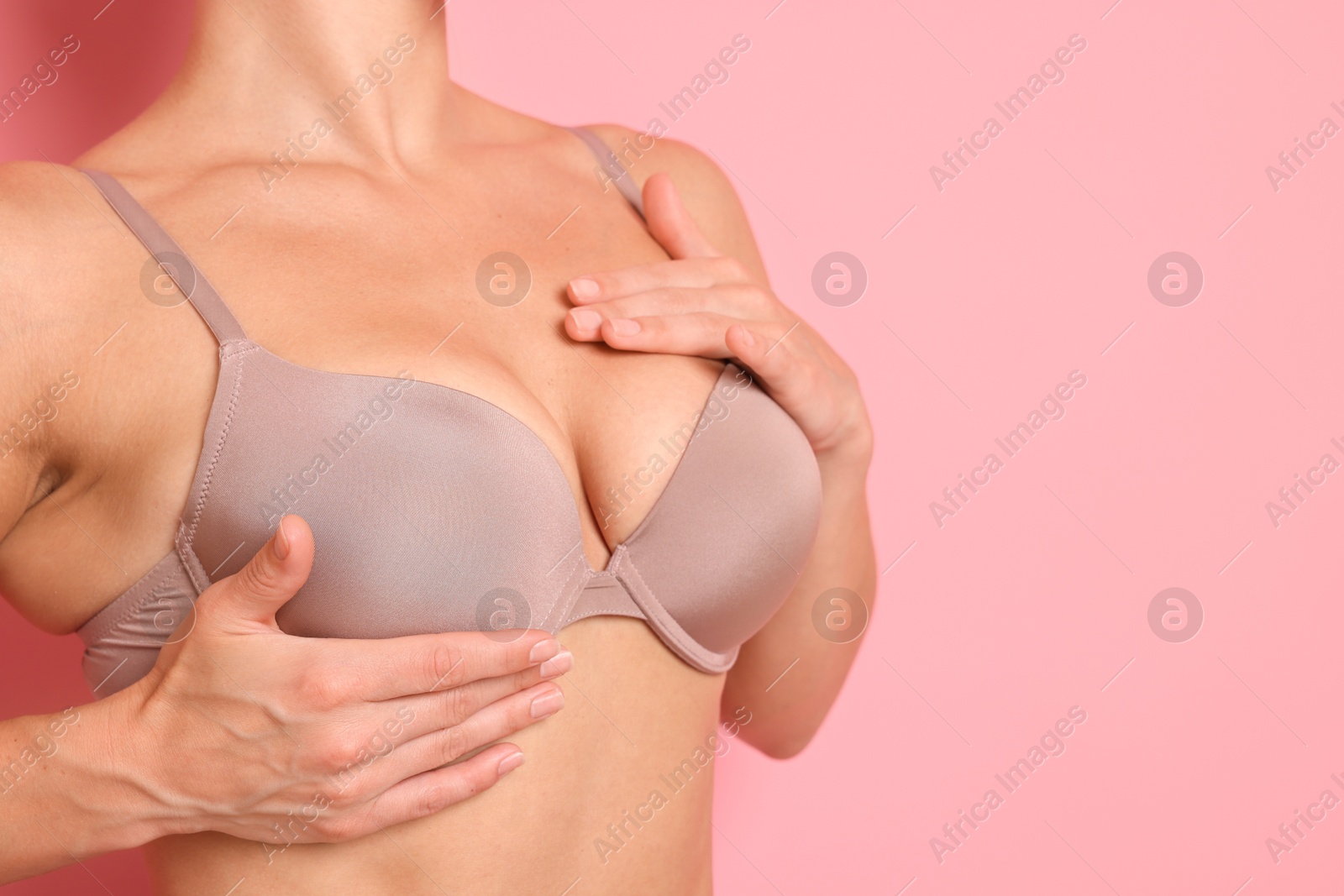 Woman wearing beautiful beige bra on pink background, closeup. Space for text Photo of Woman wearing beautiful beige bra on pink background, closeup. Space for text