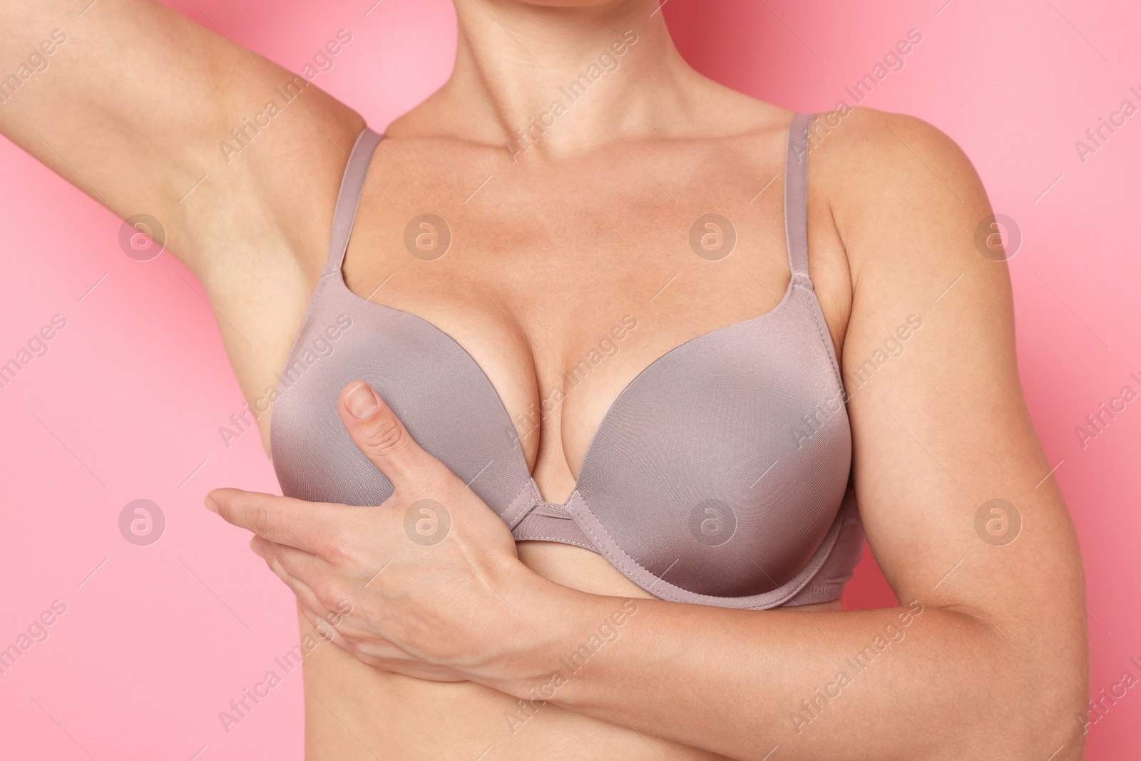 Woman wearing beautiful beige bra on pink background, closeup Photo of Woman wearing beautiful beige bra on pink background, closeup