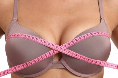 Photo of Woman in beautiful bra measuring breast circumference on white background, closeup