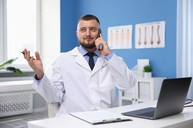 Photo of Doctor having online consultation via smartphone in clinic