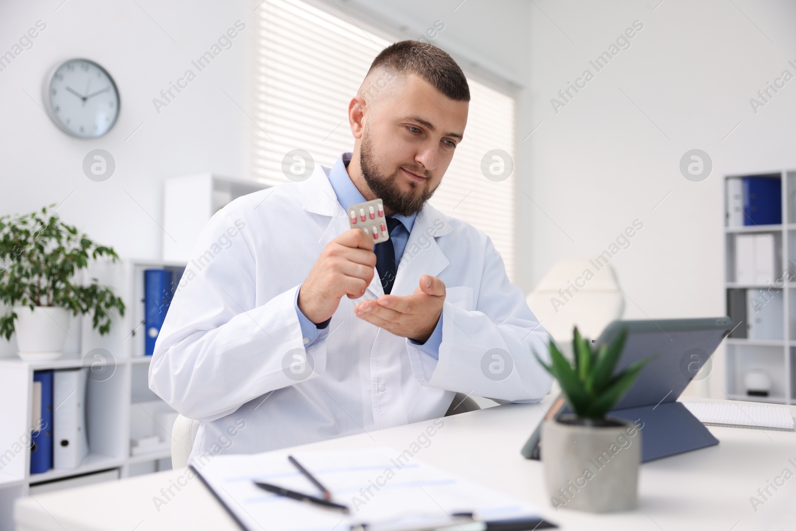 Doctor with pills having online consultation via tablet indoors Photo of Doctor with pills having online consultation via tablet indoors