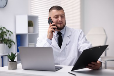 Photo of Doctor with smartphone having online consultation in clinic