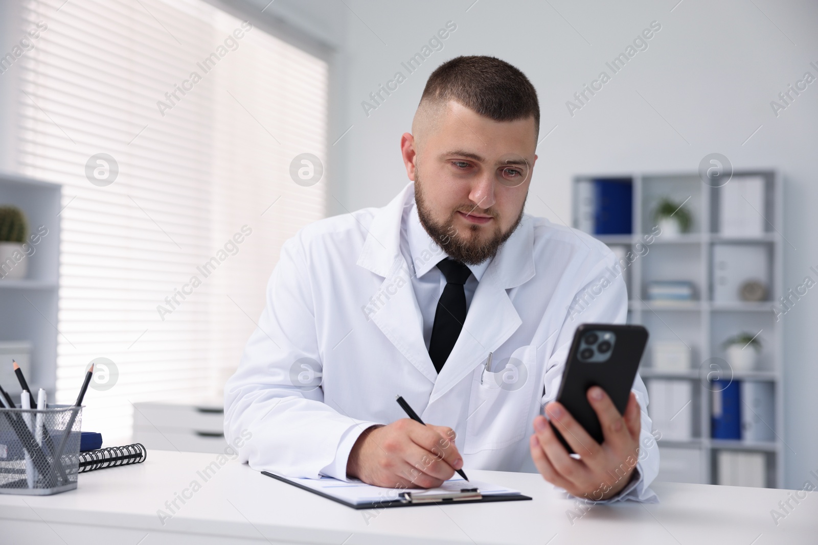 Doctor having online consultation via smartphone in clinic Photo of Doctor having online consultation via smartphone in clinic
