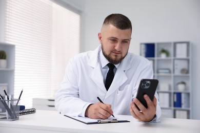 Photo of Doctor having online consultation via smartphone in clinic