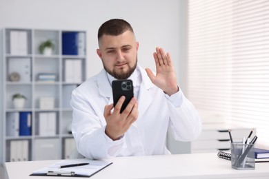 Photo of Doctor having online consultation via smartphone in clinic