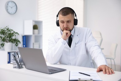 Photo of Doctor in headphones having online consultation via laptop indoors