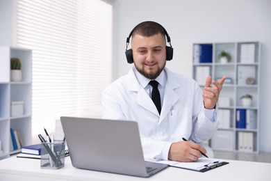 Photo of Doctor in headphones having online consultation via laptop indoors
