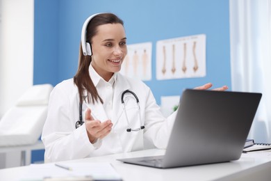 Photo of Doctor in headphones having online consultation via laptop indoors