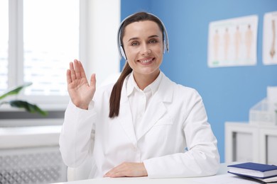 Photo of Doctor in headphones having online consultation indoors