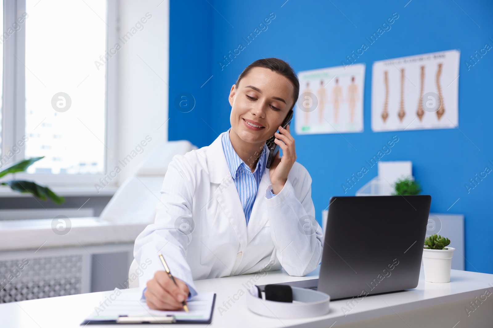 Doctor with smartphone having online consultation at table in clinic Photo of Doctor with smartphone having online consultation at table in clinic