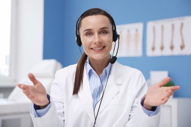 Photo of Doctor with headset having online consultation in clinic