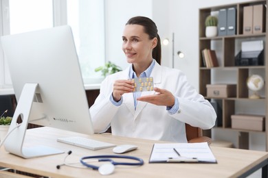 Photo of Doctor with pills having online consultation via computer in clinic