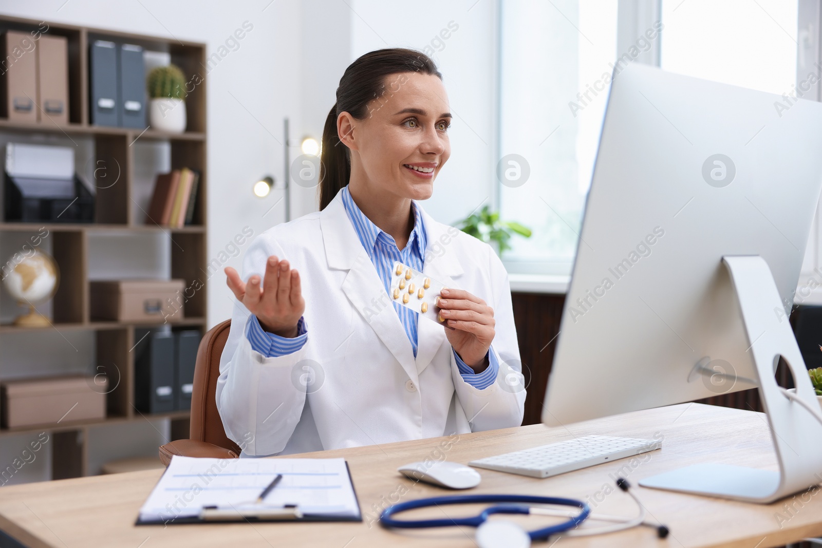Photo of Doctor with pills having online consultation via computer in clinic