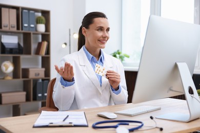 Photo of Doctor with pills having online consultation via computer in clinic