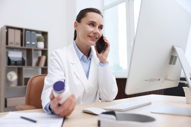 Photo of Doctor with smartphone and pills having online consultation in clinic