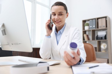 Photo of Doctor with smartphone and pills having online consultation in clinic