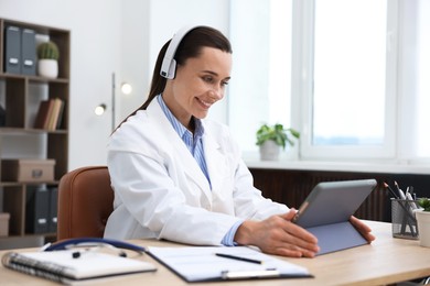 Photo of Doctor in headphones having online consultation via tablet indoors
