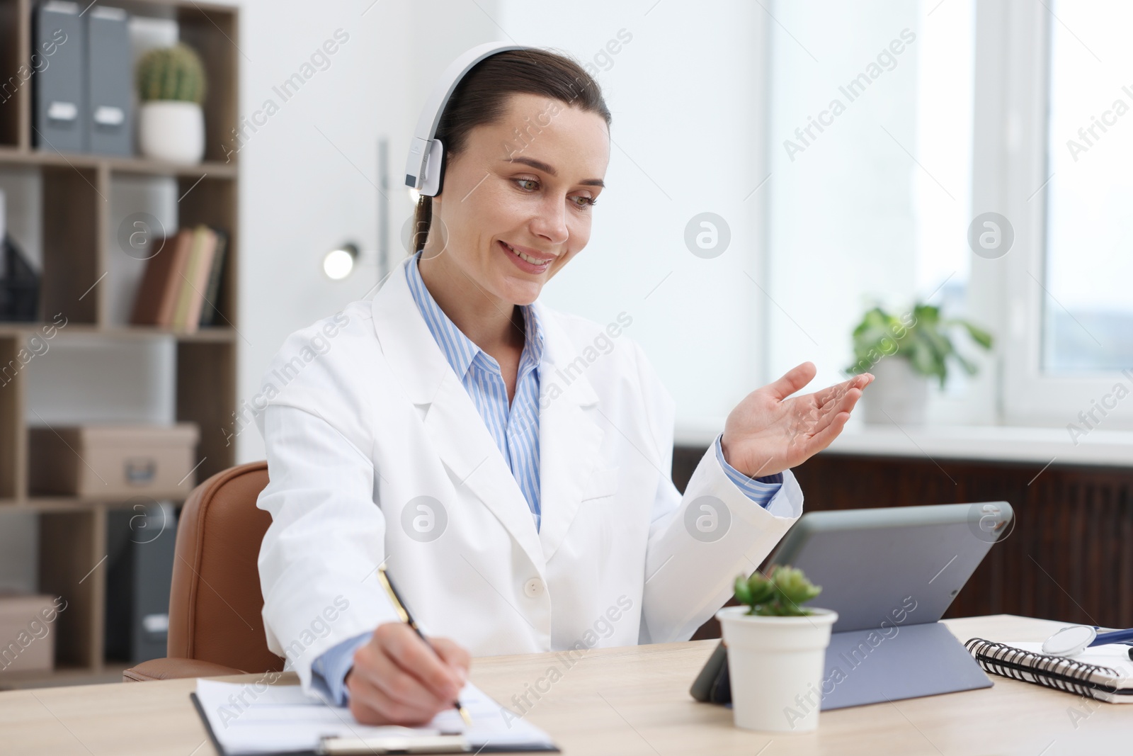 Doctor in headphones having online consultation via tablet indoors Photo of Doctor in headphones having online consultation via tablet indoors