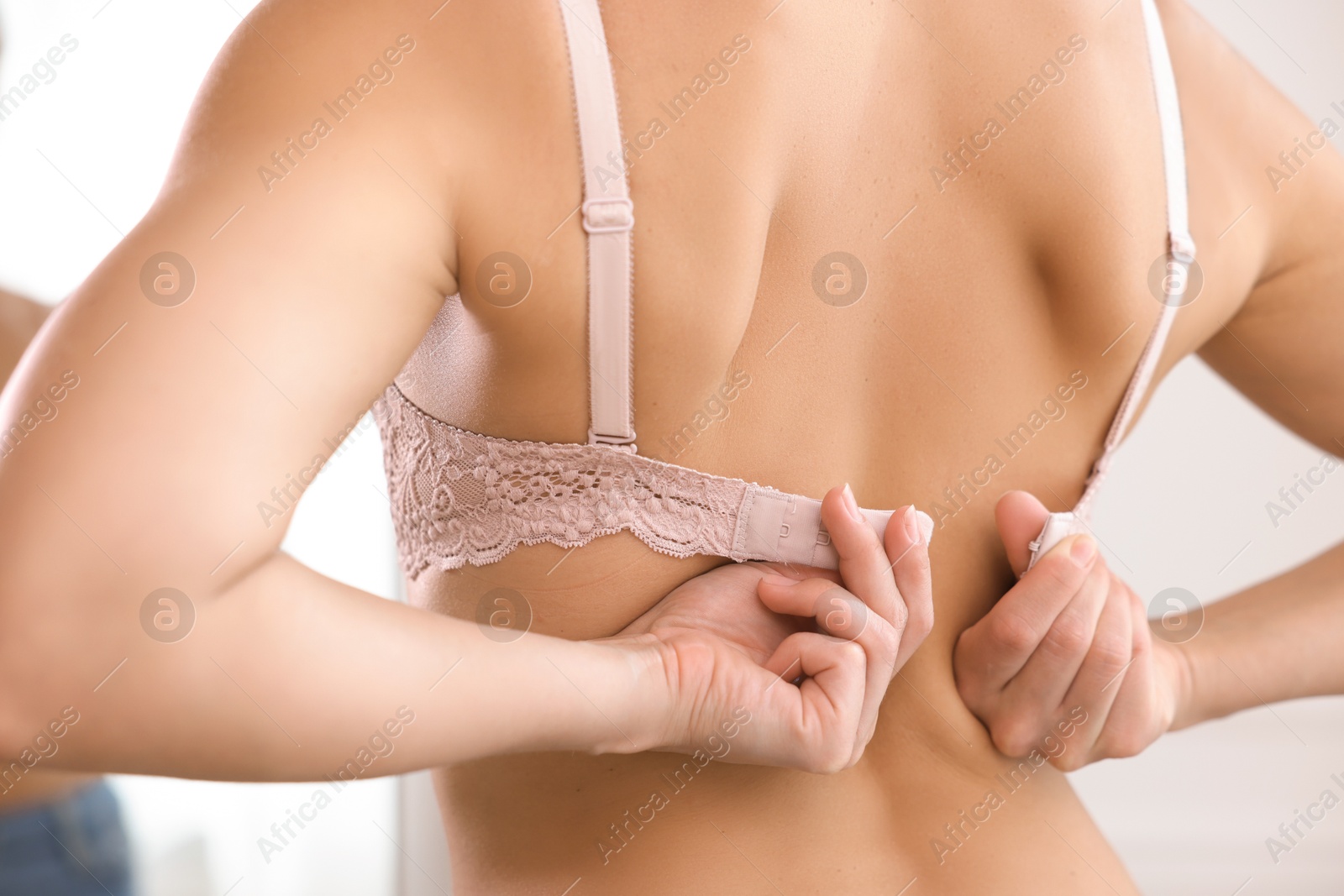 Woman putting on beautiful bra indoors, closeup Photo of Woman putting on beautiful bra indoors, closeup