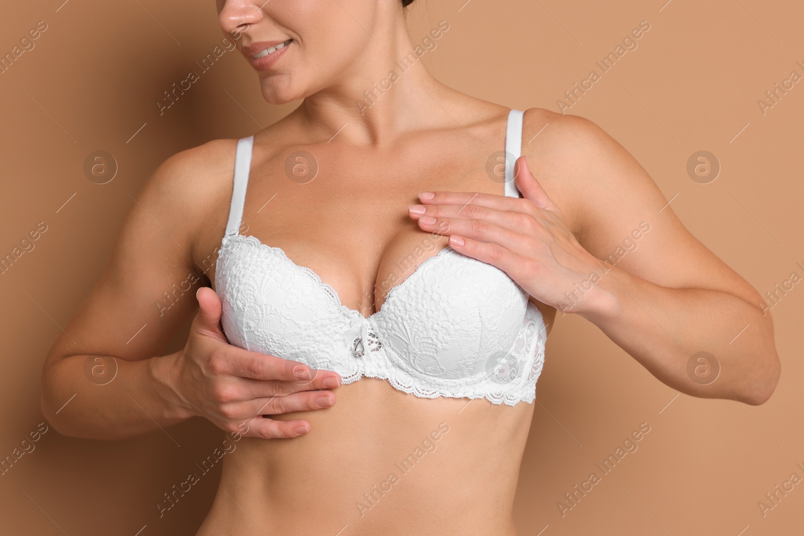 Woman wearing beautiful white bra on beige background, closeup Photo of Woman wearing beautiful white bra on beige background, closeup