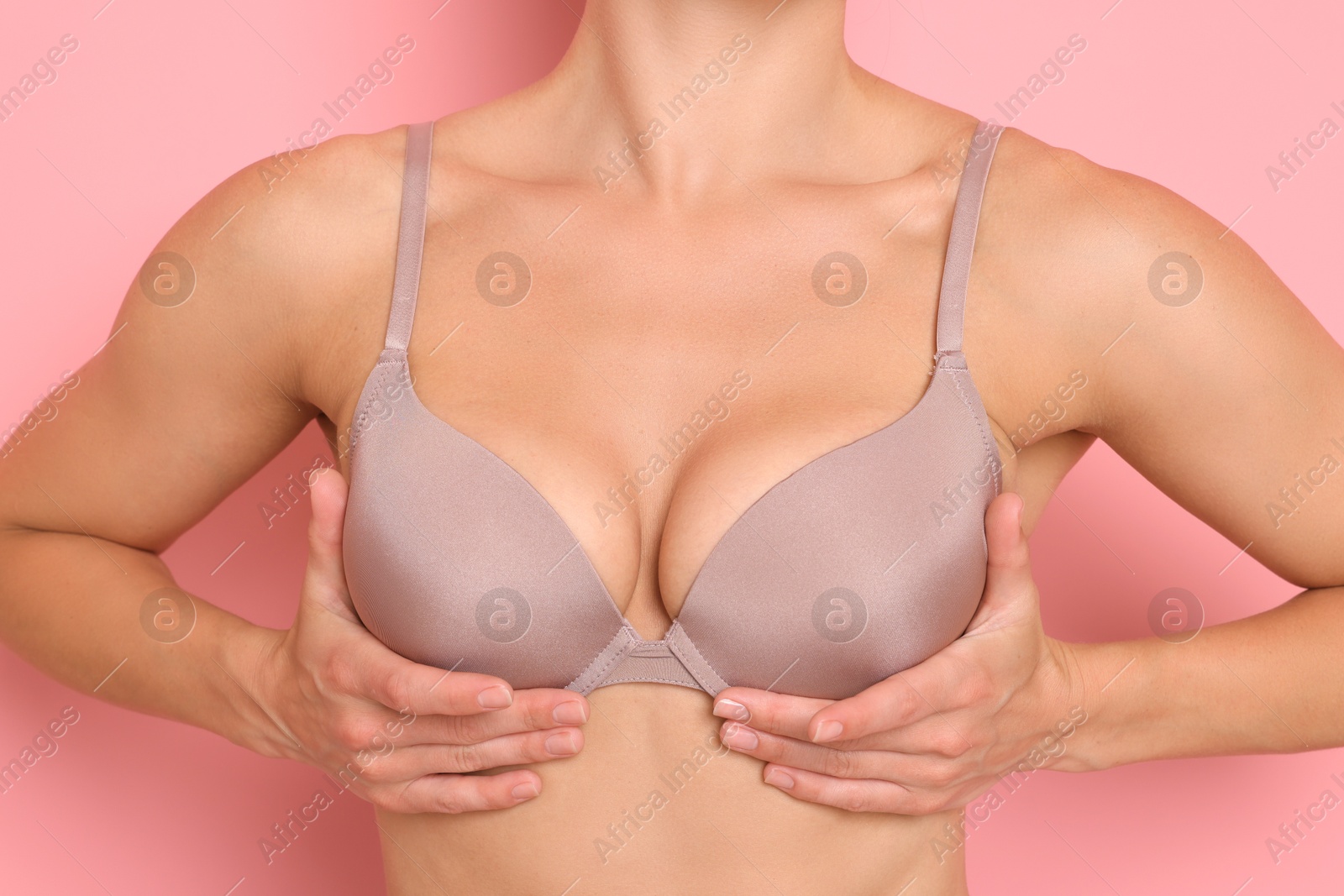 Woman wearing beautiful beige bra on pink background, closeup Photo of Woman wearing beautiful beige bra on pink background, closeup