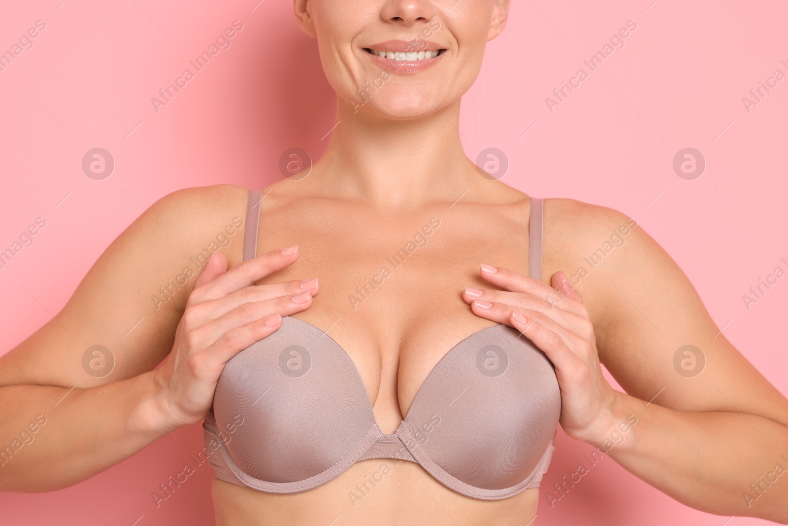 Woman wearing beautiful beige bra on pink background, closeup Photo of Woman wearing beautiful beige bra on pink background, closeup