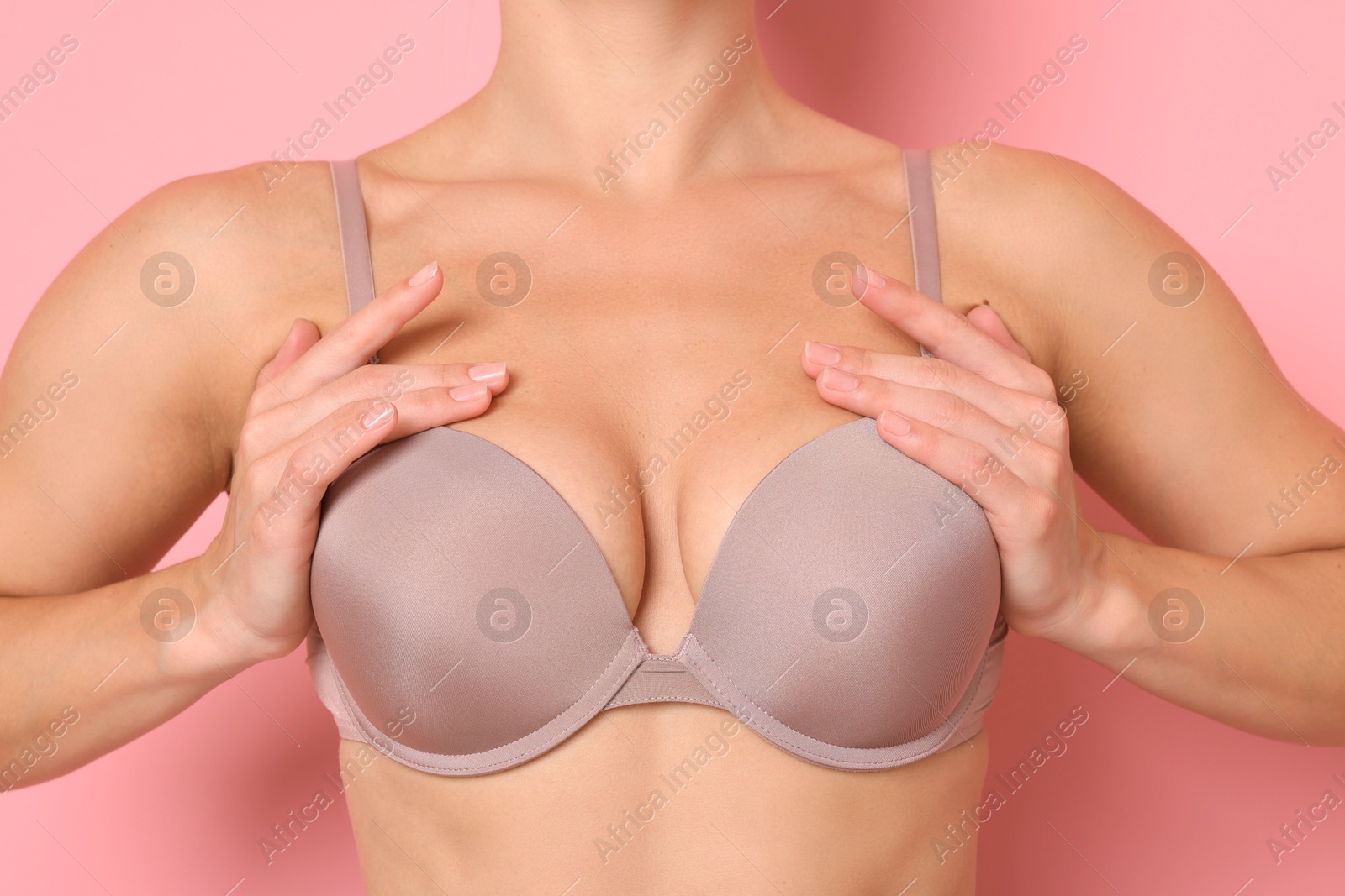 Woman wearing beautiful beige bra on pink background, closeup Photo of Woman wearing beautiful beige bra on pink background, closeup