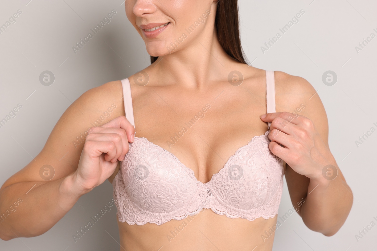Woman wearing beautiful pink bra on light grey background, closeup Photo of Woman wearing beautiful pink bra on light grey background, closeup